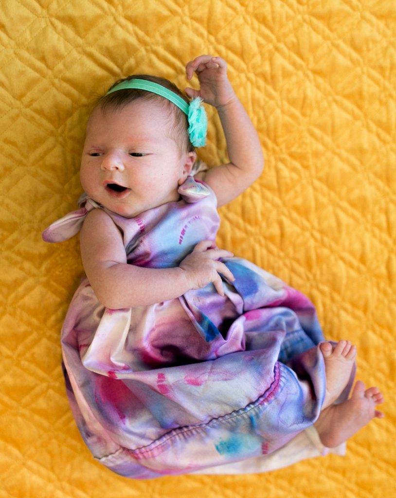 The almost-smile of a newborn. The dress was made from a pillowcase and hand dyed by Kate.