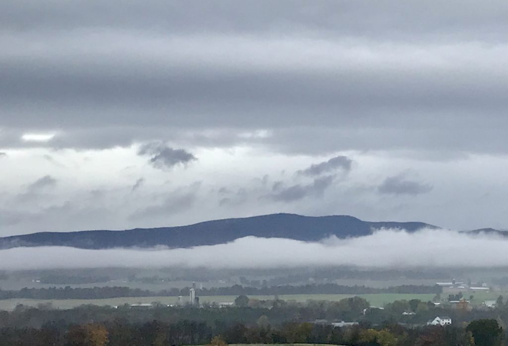 The Allegheny Mountains peek out from a layer of clouds above and below.